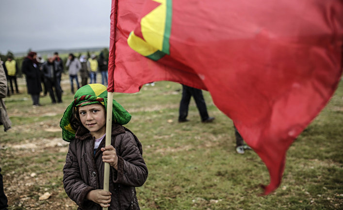 Мальчик из семьи сирийских курдов держит флаг Курдистана во время празднования Навруза в городе Кобани