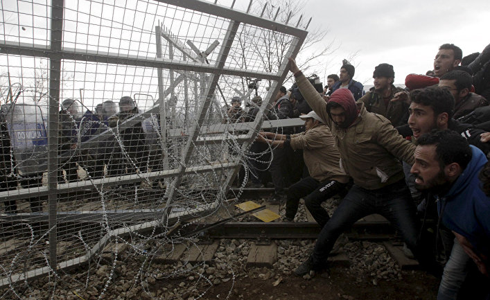 Беженцы и мигранты пытаются сломать часть забора во время протестов на границе Греции и Македонии