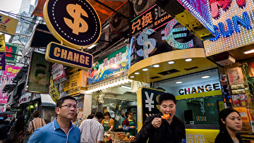 Прохожие гуляют мимо обменных пунктов в Гонконге