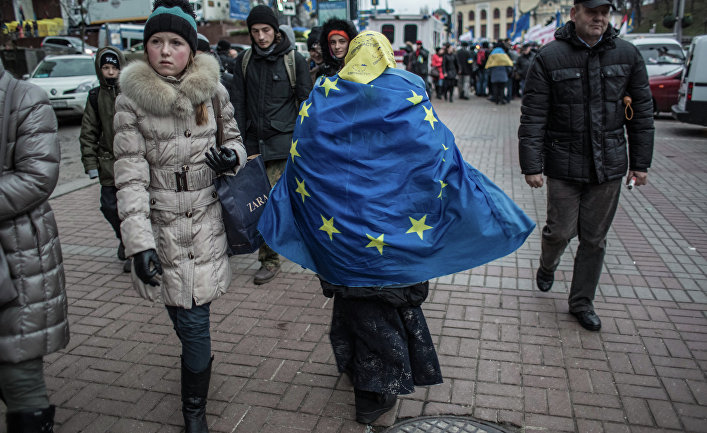 Женщина, обернувшаяся во флаг ЕС, идет по Крещатику в Киеве.
