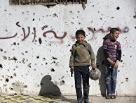 Сирийские мальчики играют в футбол возле разрушенных зданий в городе Хомс