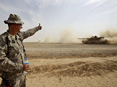 Солдат армии США дает знак экипажу танка М1А1 Abrams во время учений в Ираке
