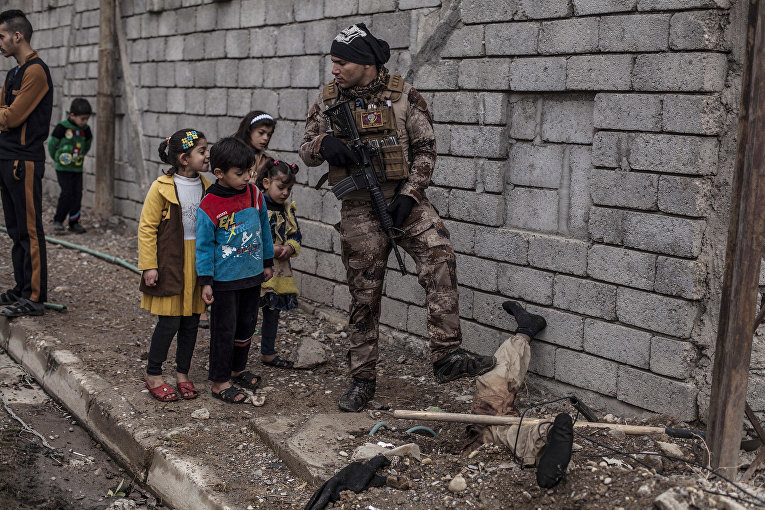 Дети рассматривают полузакопанный труп боевика ИГИЛ