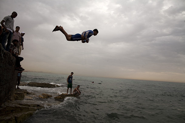 Местные жители спасаются от жары в море в Бенгази, Ливия